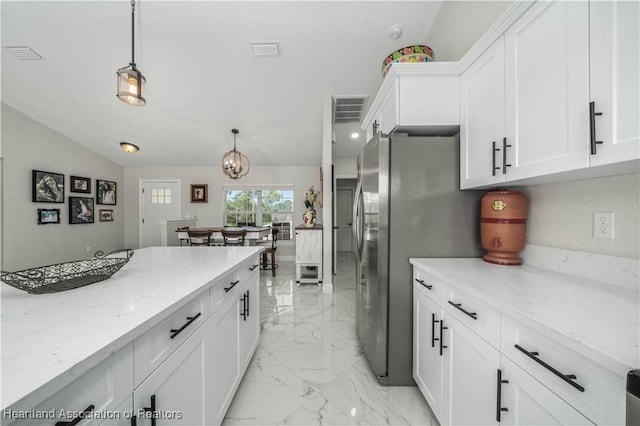 kitchen with stainless steel refrigerator, white cabinetry, light stone countertops, vaulted ceiling, and decorative light fixtures