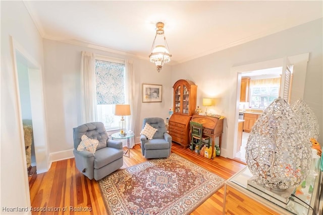 living area featuring wood-type flooring, plenty of natural light, crown molding, and a notable chandelier