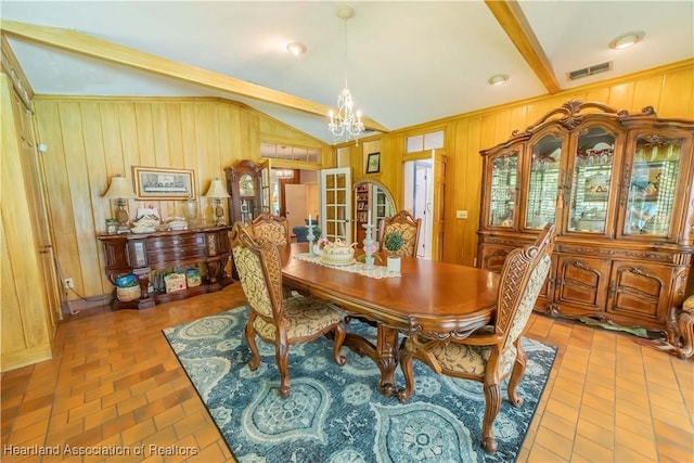 dining area featuring french doors, ornamental molding, vaulted ceiling, an inviting chandelier, and wood walls