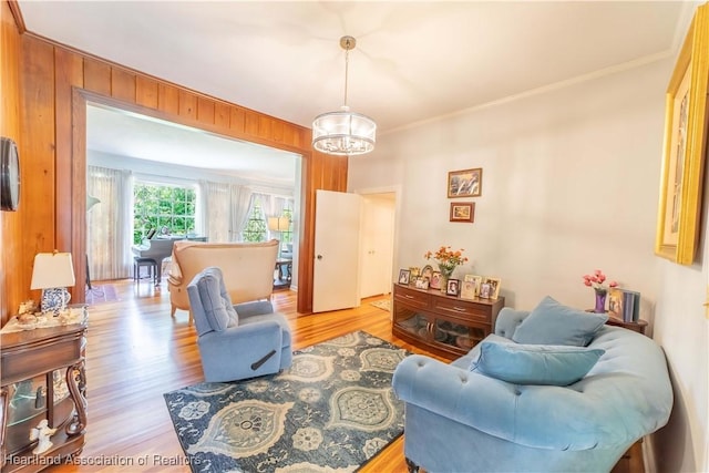 living room featuring light hardwood / wood-style floors, ornamental molding, and wooden walls