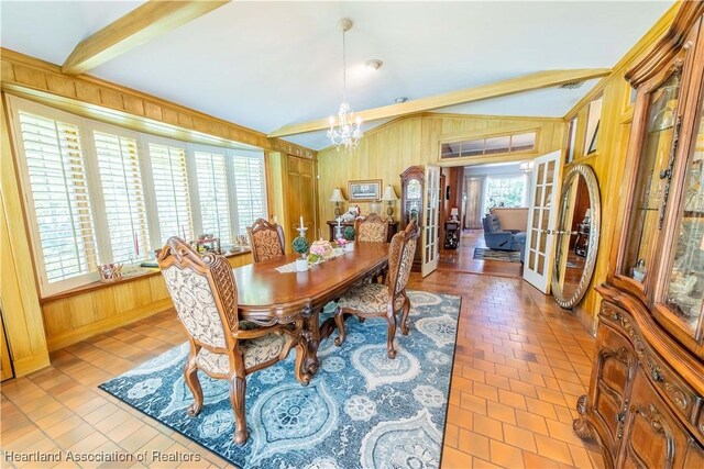 dining area featuring french doors, vaulted ceiling with beams, wooden walls, and a notable chandelier