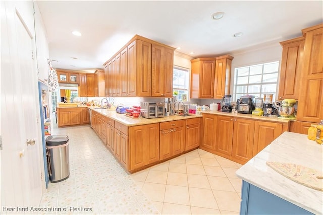 kitchen with crown molding, light tile patterned floors, and sink