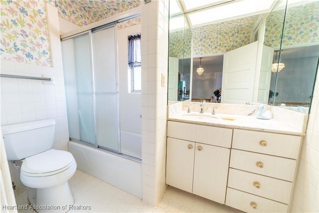 full bathroom featuring shower / bath combination with glass door, vanity, tile walls, and toilet