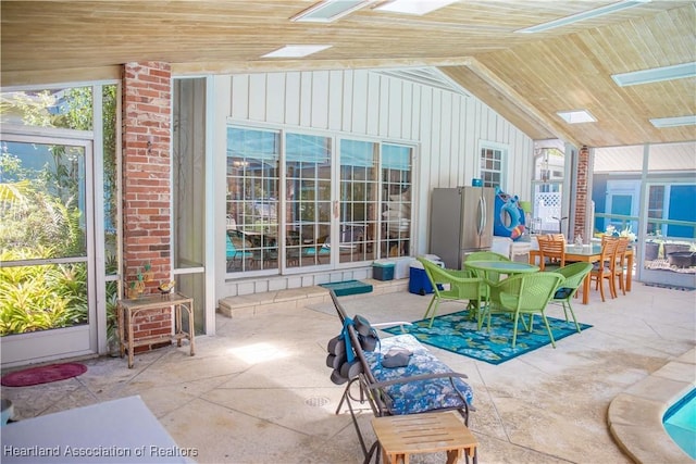 sunroom / solarium with a healthy amount of sunlight, lofted ceiling, and wood ceiling