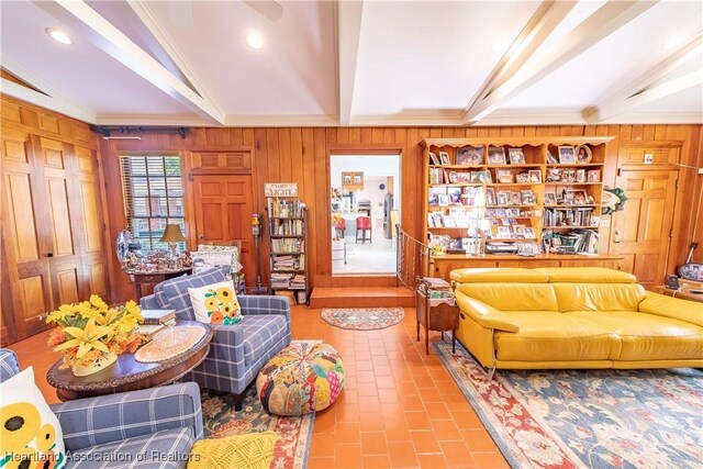 living room featuring vaulted ceiling with beams, wooden walls, and crown molding