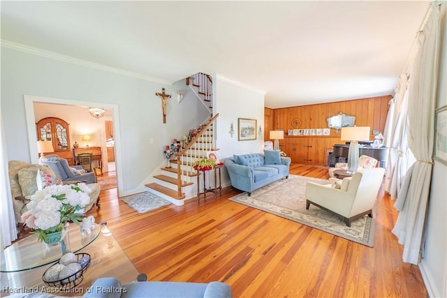 living room with wood walls, light hardwood / wood-style floors, and ornamental molding