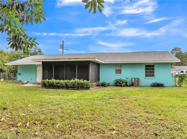 rear view of house with a sunroom, central AC unit, and a lawn