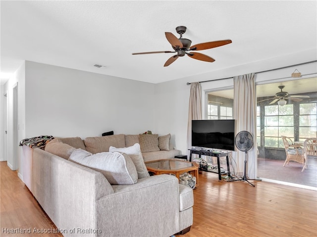 living room with a textured ceiling, light hardwood / wood-style floors, and ceiling fan