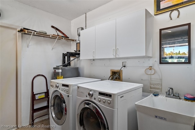 laundry room featuring water heater, washing machine and dryer, a sink, and cabinet space