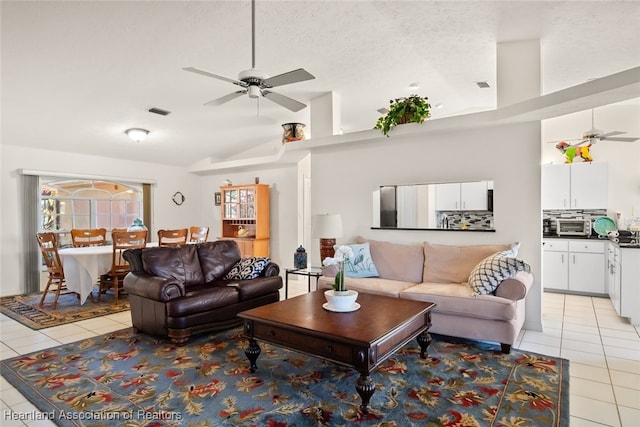 living room featuring light tile patterned flooring, vaulted ceiling, visible vents, and ceiling fan