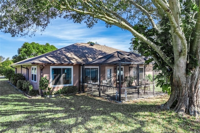 view of front of house featuring a patio, a lanai, a shingled roof, stucco siding, and a front yard