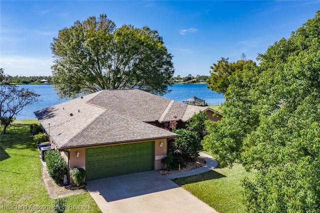 exterior space with a garage, a water view, driveway, and a front lawn