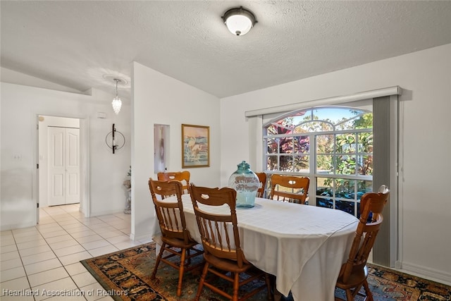 dining space with light tile patterned floors, a textured ceiling, and lofted ceiling