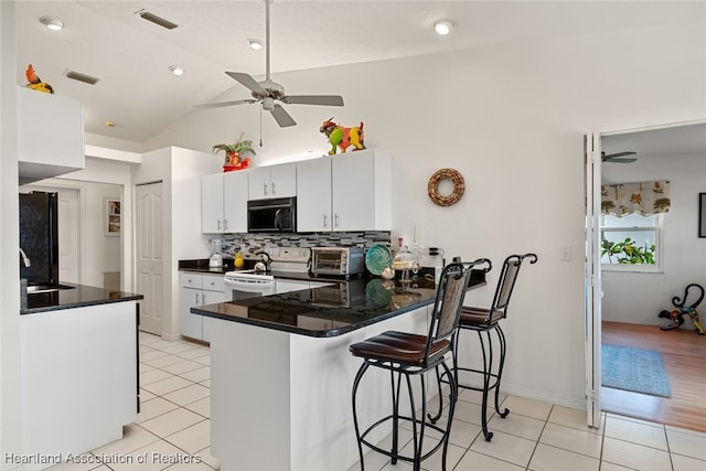 kitchen featuring a peninsula, visible vents, white cabinetry, black appliances, and dark countertops