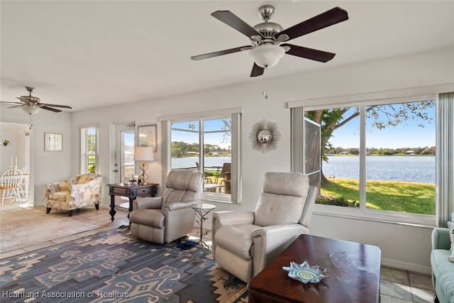 interior space with a ceiling fan, a water view, baseboards, and tile patterned floors