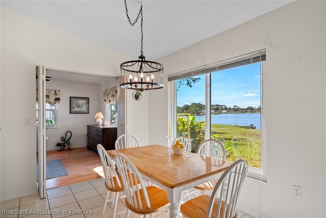 dining space featuring a water view and light tile patterned flooring