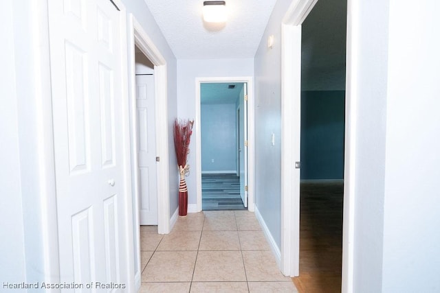 hallway with light tile patterned floors and a textured ceiling