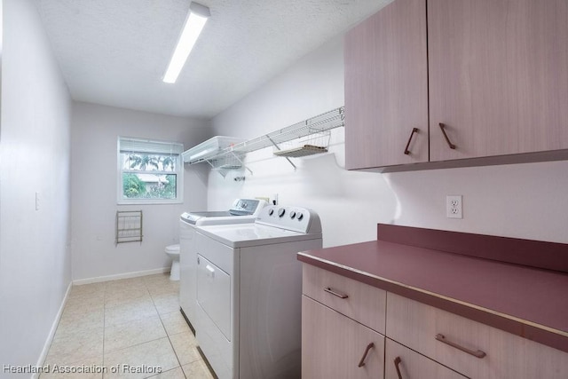 laundry area with washing machine and dryer, light tile patterned floors, and a textured ceiling