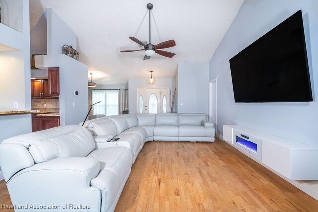 unfurnished living room featuring light hardwood / wood-style floors, ceiling fan, and lofted ceiling