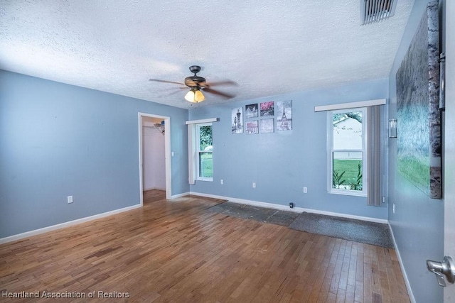 unfurnished room with ceiling fan, hardwood / wood-style floors, and a textured ceiling