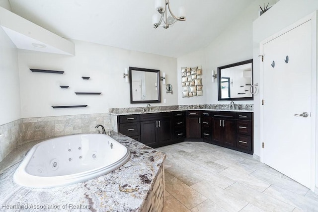 bathroom featuring tiled tub, vanity, and an inviting chandelier