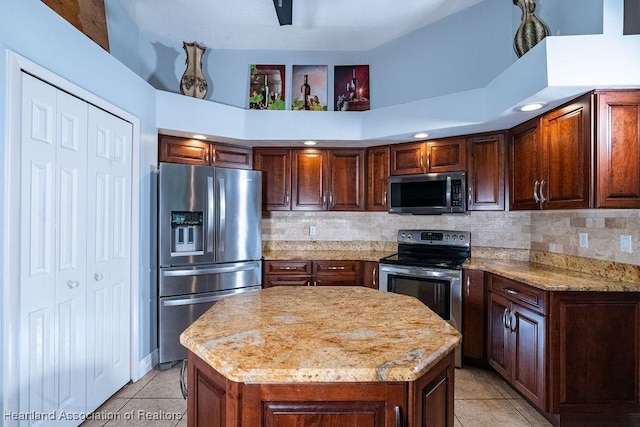 kitchen with a towering ceiling, stainless steel appliances, light tile patterned floors, and a kitchen island