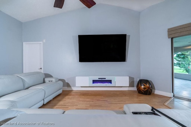 living room with ceiling fan, wood-type flooring, and vaulted ceiling