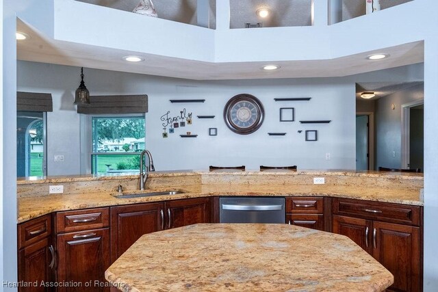 kitchen featuring stainless steel dishwasher, dark brown cabinets, light stone counters, and sink