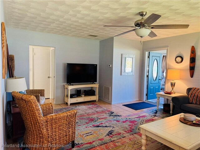 living room featuring light tile patterned floors, a textured ceiling, and ceiling fan