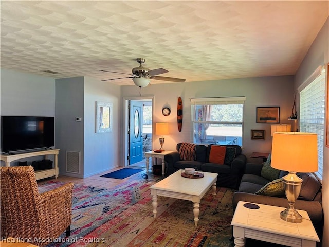 living room featuring ceiling fan, tile patterned floors, and a textured ceiling