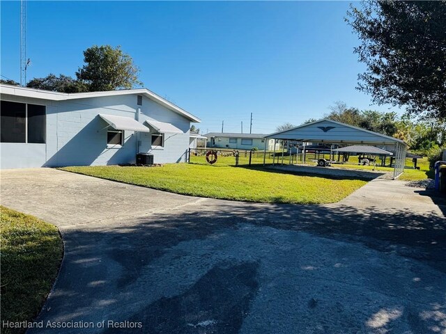 view of home's exterior with a carport, a lawn, and central AC