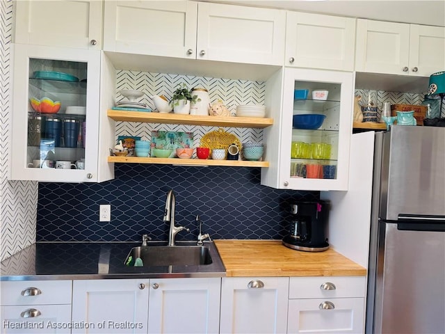 kitchen featuring white cabinetry, sink, and stainless steel fridge