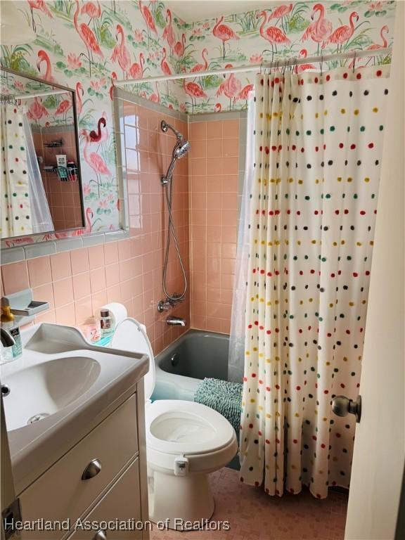 full bathroom with vanity, toilet, tile walls, and shower / bath combo