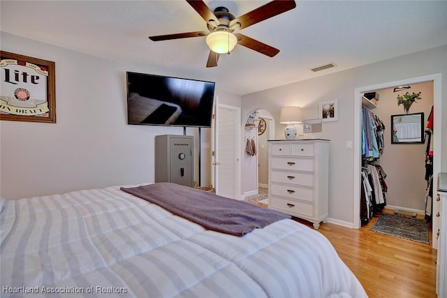 bedroom with a walk in closet, light hardwood / wood-style flooring, a closet, and ceiling fan