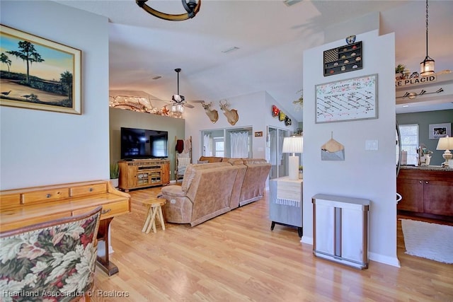 living room featuring ceiling fan, vaulted ceiling, and light wood-type flooring