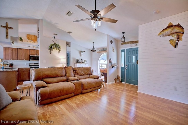 living room featuring sink, vaulted ceiling, and light wood-type flooring