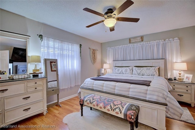 bedroom with ceiling fan, light hardwood / wood-style floors, and a textured ceiling