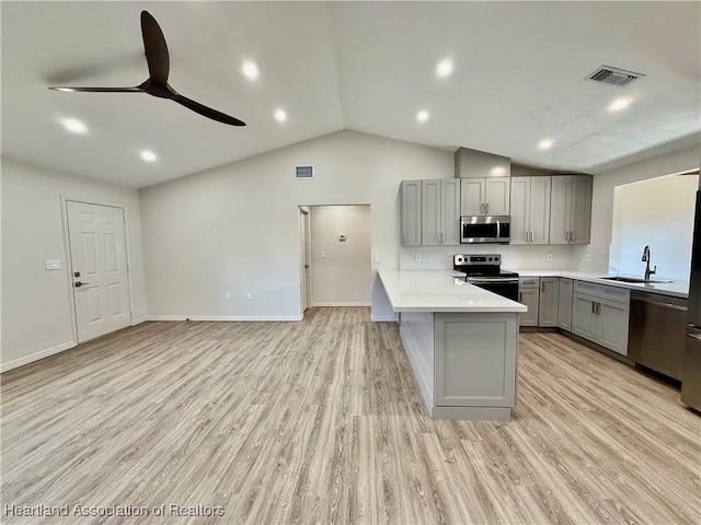 kitchen with appliances with stainless steel finishes, sink, gray cabinetry, kitchen peninsula, and light wood-type flooring