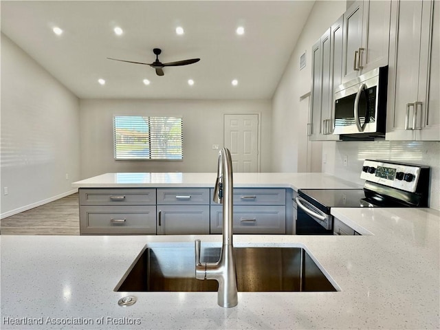 kitchen featuring light stone counters, appliances with stainless steel finishes, sink, and gray cabinetry