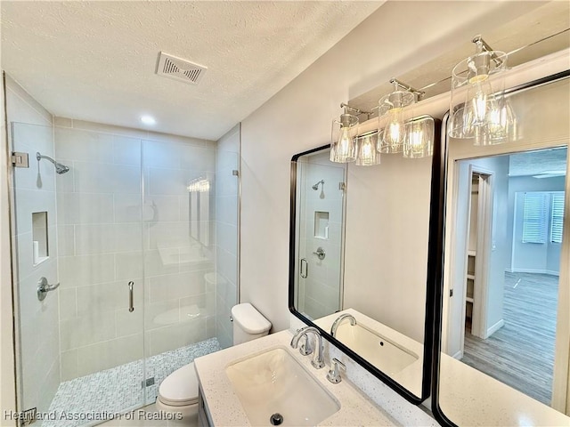 bathroom with walk in shower, toilet, wood-type flooring, a textured ceiling, and vanity