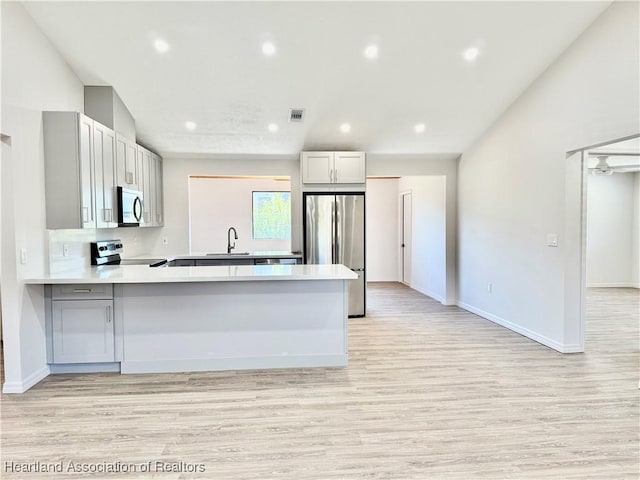 kitchen featuring light hardwood / wood-style floors, appliances with stainless steel finishes, kitchen peninsula, and sink