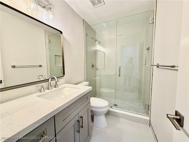 bathroom featuring toilet, a shower with shower door, a textured ceiling, vanity, and tile patterned flooring