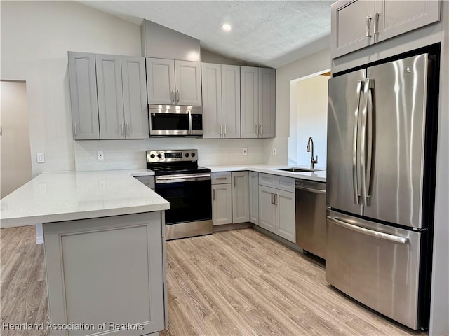 kitchen with stainless steel appliances, sink, gray cabinetry, and kitchen peninsula