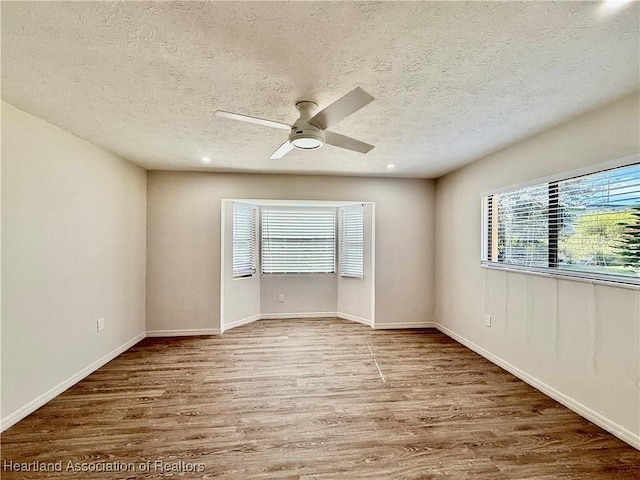 unfurnished room featuring hardwood / wood-style flooring, a textured ceiling, and a wealth of natural light