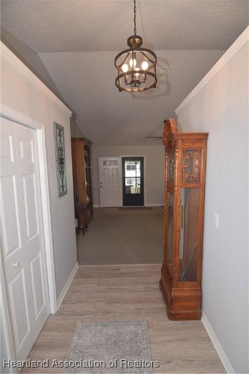 hallway featuring vaulted ceiling, light wood-type flooring, and a chandelier