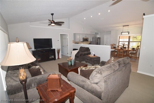 living room with a textured ceiling, ceiling fan, light carpet, and vaulted ceiling