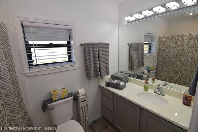 bathroom with walk in shower, vanity, and toilet