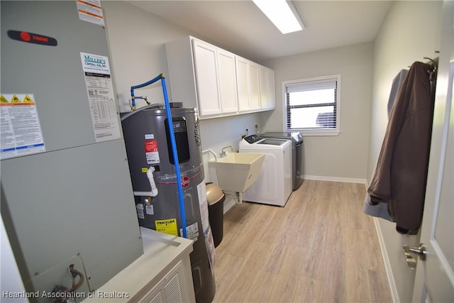 laundry room featuring cabinets, sink, water heater, independent washer and dryer, and light hardwood / wood-style floors