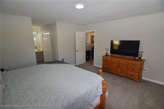 carpeted bedroom featuring ensuite bath and a textured ceiling