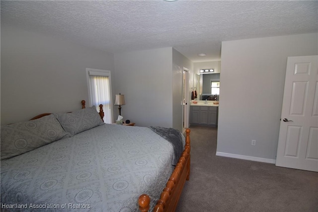 bedroom with a textured ceiling, ensuite bathroom, dark carpet, and multiple windows